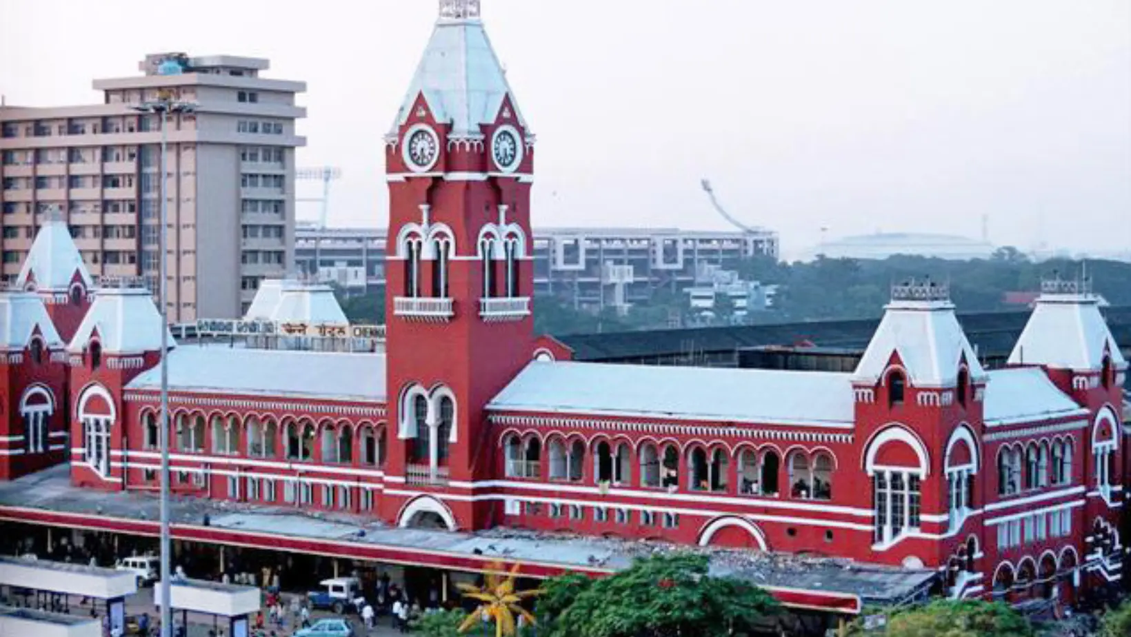 A red building featuring a clock tower adorned with a large clock, set against a clear blue sky.